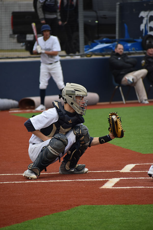 Strike One \\ Catching a pitch, freshman Sammy Harris positions himself in a wide stance to snag the baseball. He offers advice on what baseball players can do to pass the time during a rain delay.