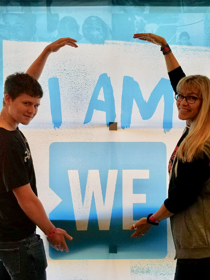 I am ready // Walking into the venue, sophomore Trevor Wischnewsky and Spanish teacher Mrs. Jamè Farrar stop to take a picture by the charities slogan. Wischnewsky was chosen to attend the WE charity-hosted event at the Curtis Culwell Center in Garland, Texas March 21.