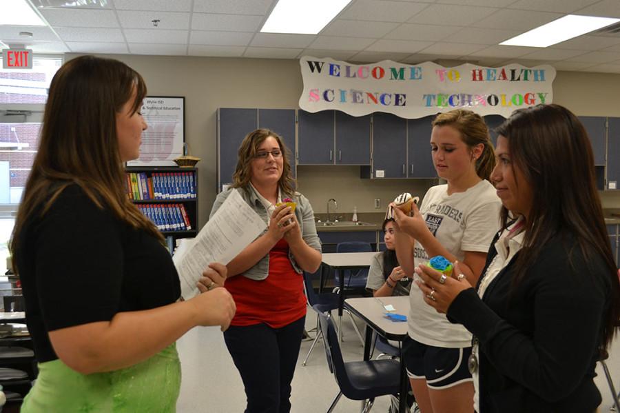 Sweet and power // Receiving their new officer positions, members of HOSA take bites representing lighting of a candle of their cupcakes.