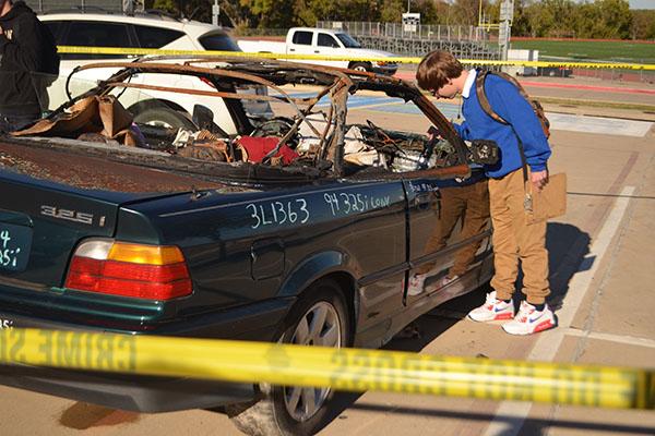 Fleshing out the crime scene \\ Looking closely for a clue to the case, senior Kyle Flesch investigates the melted passenger seat airbag during David Lanman’s eighth period forensics class. The students will work crime scenes throughout the year to figure out the story behind Lyle and Louise and what led to the family’s demise. 
