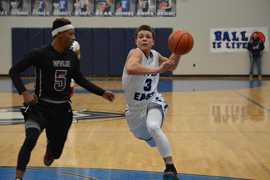 Quick trip // Passing the ball to senior Robert Benners, senior Xavier Hopkins is accidentally tripped by a Wylie High player but quickly recovered to help Benners make the basket.
