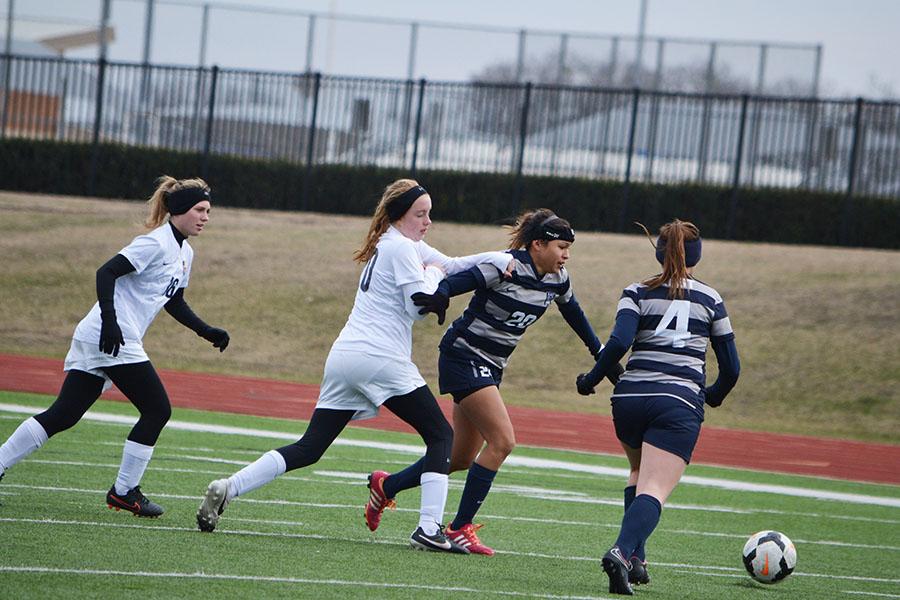Tough it out // Holding off a John Paul II opponent, center defender Samantha Ramirez races to the ball at the Jan. 10 game against John Paul II High School. The close game ended 1-0 with the Raider varsity team taking the win.