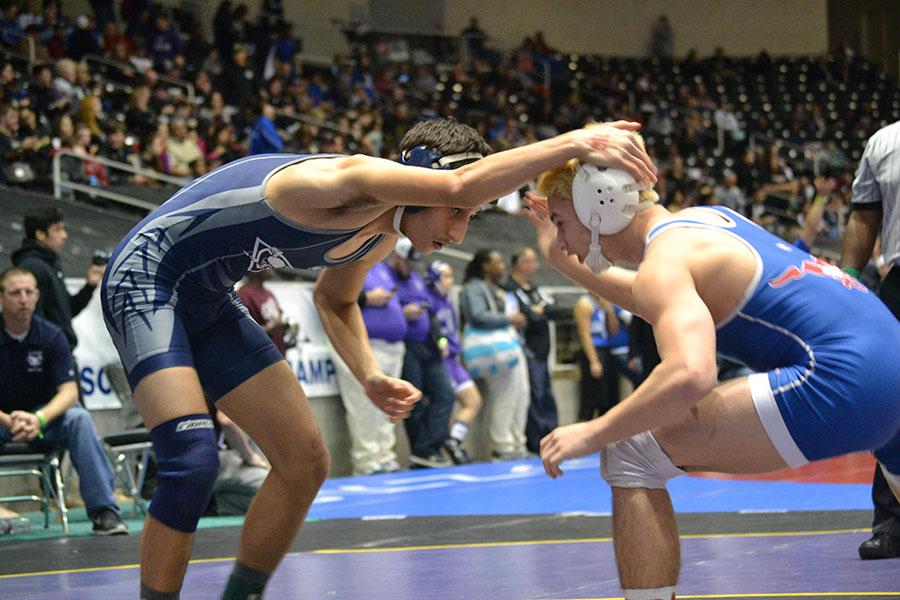 Second match \\ Slapping his opponents head gear, junior Aram Amin tries to distract him, as most wrestlers do. Amin lost his match at State.