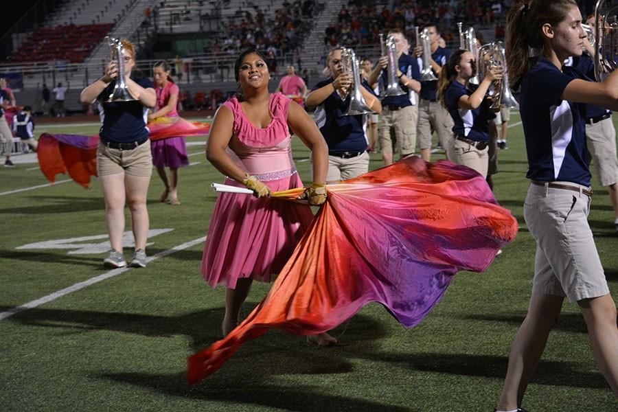 All eyes on Alice \ Performing their first half time performance in their uniforms, sophomore Alice Castro waves the flag to the band’s Dare to Dream song. 