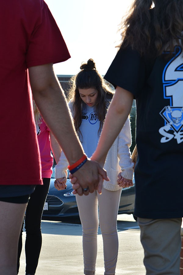 Hand in hand \\ Leading the senior group in prayer, senior Mikaila Summers prays over the school at See You at the Pole. Students met out at the front benches Sept. 23 for worship, service and prayer.