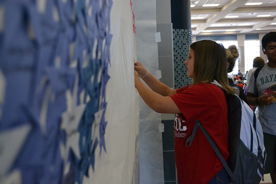 Remember, write and glue \\ Gingerly placing the name of a victim of the Sept. 11, 2001 terrorist attacks, sophomore Alexis Allen participates in the Student Council activity. With red, white and blue stars with names of victims written on them, the student body created an American flag.