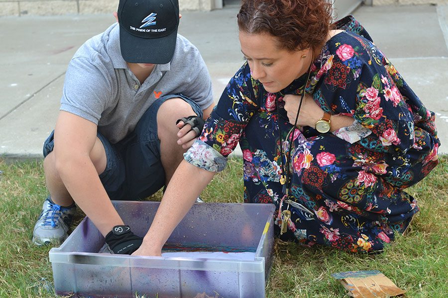 Helping Hands \\ Art I teacher Mrs. Tigert helps freshman Kristian Godfrey dip paper into his spray paint marble design. 