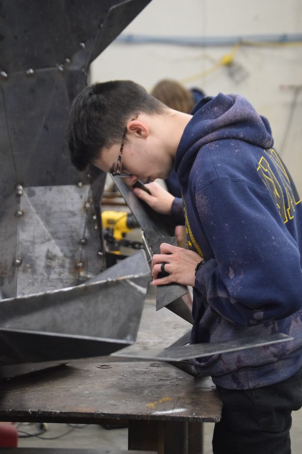Wonder welder // Adjusting the measurements, senior Matthew Welsh attempts to assemble the jaw for the welding project. The students have been constructing it since October.