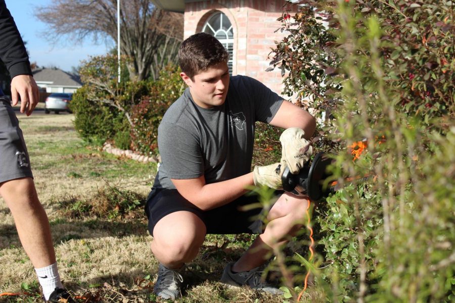 Weed-eater // Senior Jacob Pryor uses an electric hedge trimmer to shape Mrs. Jennifer Holcomb’s bushes. Mrs. Holcomb was recently diagnosed with cancer in her colon, back and liver. “I was so touched at their generosity and outreach to me,” Holcomb said.