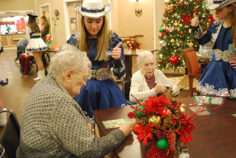 Season of service \\ Giving a thumbs up as her resident places her marker on the correct spot, sophomore Halli Fulton volunteers at Founders Plaza Nursing home along with the Sapphires for their service project. The drill team spent the day hanging out, singing Christmas songs, and handing out gifts to the residents there. 