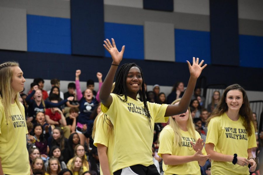 Get set \\ Waving to the audience, sophomore varsity volleyball player Nyle Mathis steps forward as her name is announced during the varsity team introductions. The varsity girls team thanked students for their constant support. 