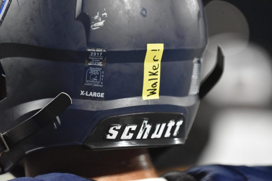 Golden moment \\ Waiting for the next play, varsity football players sport their new yellow stickers on the back of their helmet Sept. 6 at the Gold Out game. Players placed these stickers on the backs of their helmets to honor local victims of pediatric cancer. “I felt like I was really showing support for people who were put in situations they can’t control,” varsity player Collen Covington said.
