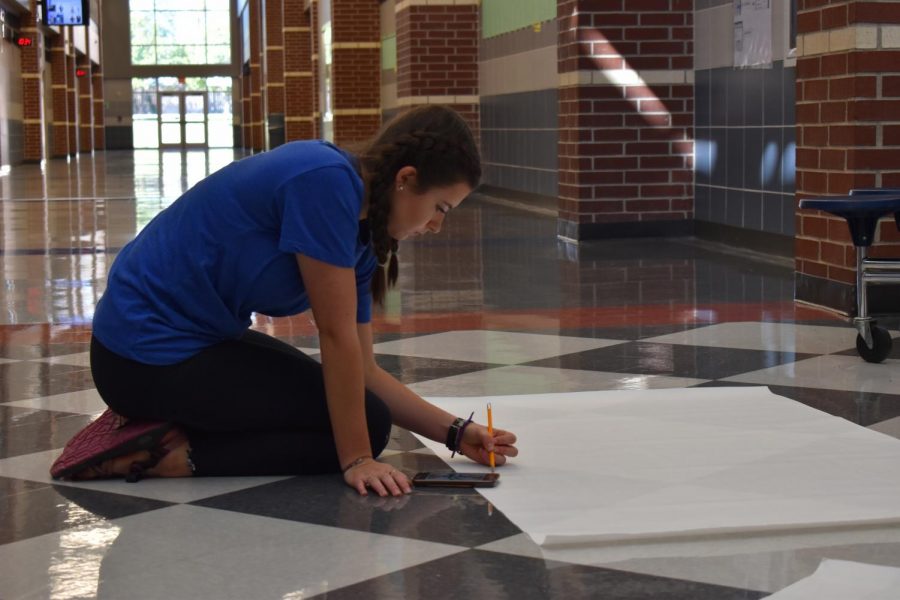 Monster maker \\ National Honor Society president Angela LaMarche sketches out a character from the Pixar movie, Monsters University to decorate the NHS section of the hall for Homecoming week. All decorations related to the theme “Lights, Camera, Raiders,” and groups, including NHS, worked for hours Saturday, Oct. 12. “I was thinking about a movie that would somehow relate to NHS and Monsters University just popped in my head,” Lamarche said. “Thanks to all the people that came to help on a Saturday, we got the entire thing done from start to finish in five hours and I was super impressed.”