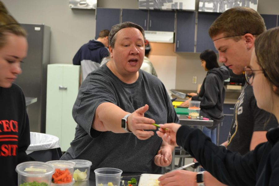 Bon Appeteach \\ Chef Jennifer Carlin shows her students how to properly cut peas. Groups of three cut vegetables to be used for making rice. “Fried rice is a lengthy process that has a lot of steps. Today they are preparing, so tomorrow they can cook the rice,” Carlin said. 
