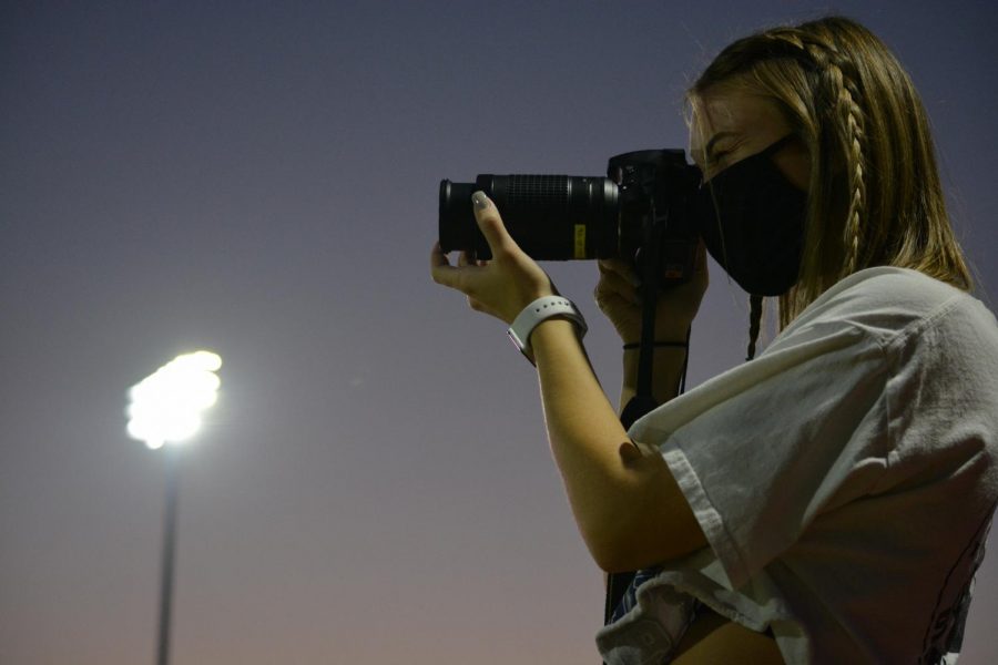 Focus on whats important \\ 
Senior yearbook student Piper Deneault shoots pictures of the homecoming royalty coronation.