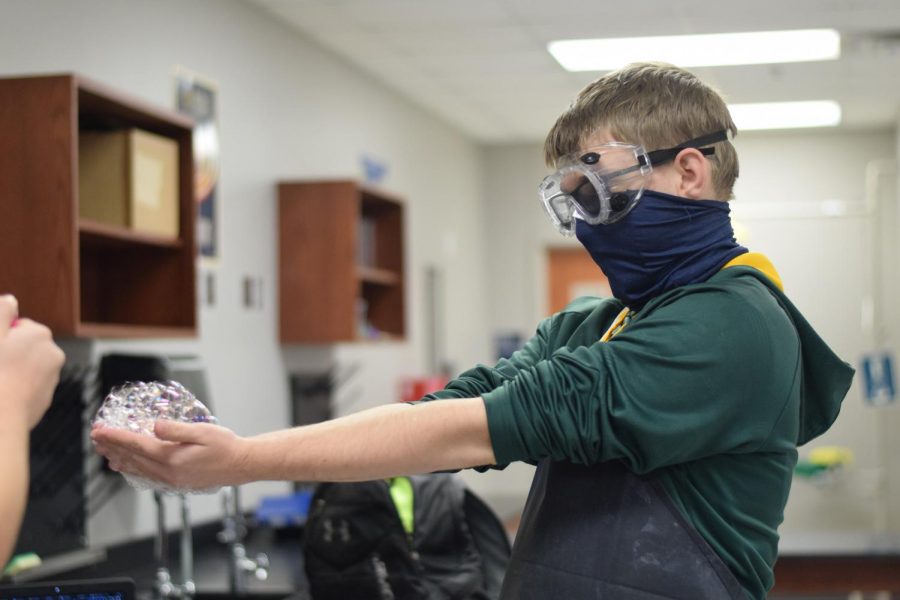 Burst your bubble \\ Sophomore Bret Tomaszewski prepares to have the butane gas-filled bubbles in his hands lit by Miss Molly Brinkley in her fourth-period chemistry class Dec. 3. “My favorite part of chemistry is getting to do the labs,” Tomaszewski said.
