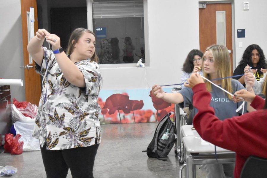 Keeping mum \\ Agriculture teacher Ms. Valerie Turner explains how to create braids for mums in her floral design class. “It was very fun to get to make a mum and experience it and the process of making one was super cool,” freshman Marisol Ruiz said.