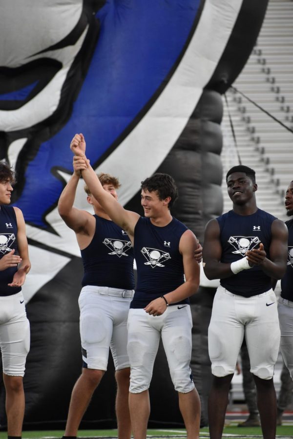 Power pose \\ Celebrating each other as their names are called, sophomore Sean Figueroa and junior Westin Waters stand alongside the other varsity football players at Meet the Raider Aug. 19. 