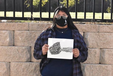 Tiger queen \\ Sophomore Heidi Martinez holds up her first place winning artwork for the National Art Honor Society Inktober contest. Her picture reveals a tiger with a muzzle over its mouth and human hands holding the muzzle in place.