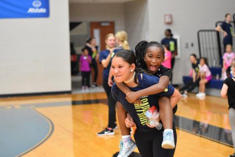 Mini me \\ Junior Mikayla Neveloff runs around the gym with her Jr. Jewel during a water break. Sapphires host this clinic twice a year to raise money and give girls a chance to dance with older girls. 