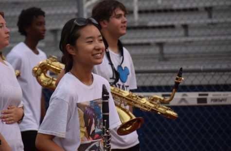Smiling Soloist \\ Running through the show at the JV stadium, sophomore Alex Tran happily carries her instrument, the soprano clarinet, on which she plays her solo in the opener of the show.