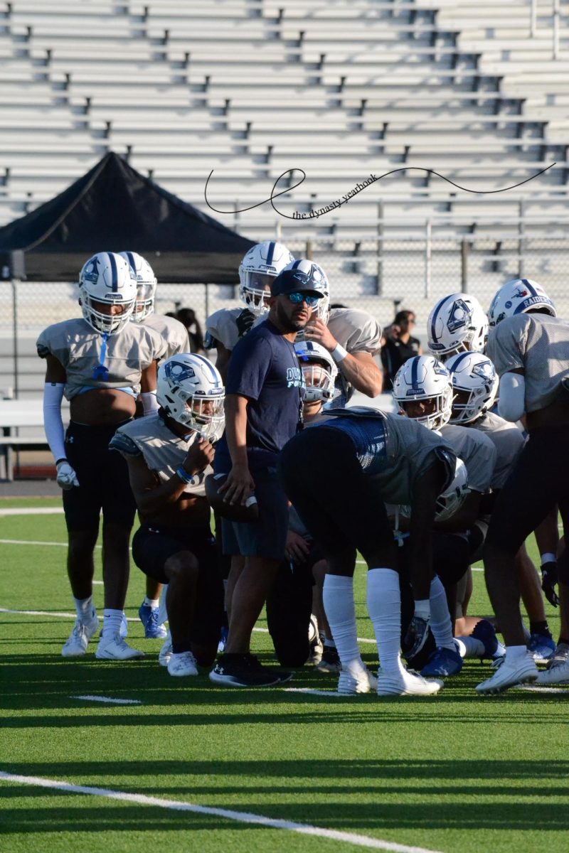 Scrimmage+scuttlebutt+%5C%5C+The+Varsity+football+team+huddles+around+coach+Marcus+Gold+after+stretching+before+scrimmage+against+Irving.+After+the+scrimmage%2C+the+players+were+announced+at+Meet+the+Raider.+The+game+was+also+the+first+of+many+Thursday+night+games+of+the+season.+My+favorite+cheer+to+hear+when+Im+down+on+the+field+is+the+DUBeast+chant+from+the+student+section%2C+Micheal+Henderson+said.+