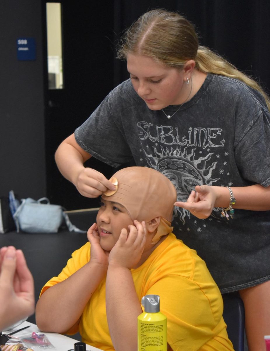 Wearing many hats \\ As associate director of the Theater’s 2024 Murder Mystery Dinner show, The Dead Will Die, senior Addi Autrey helps Micah Balatbat get into costume as Charlie Brown Sept. 20. 